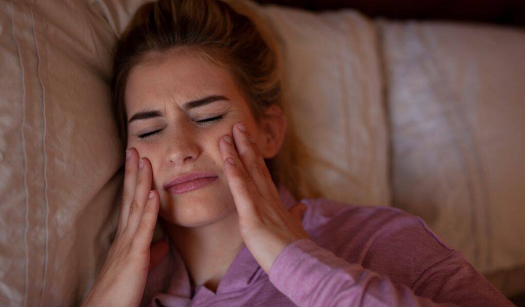 Patient applying at-home care for TMJ jaw pain